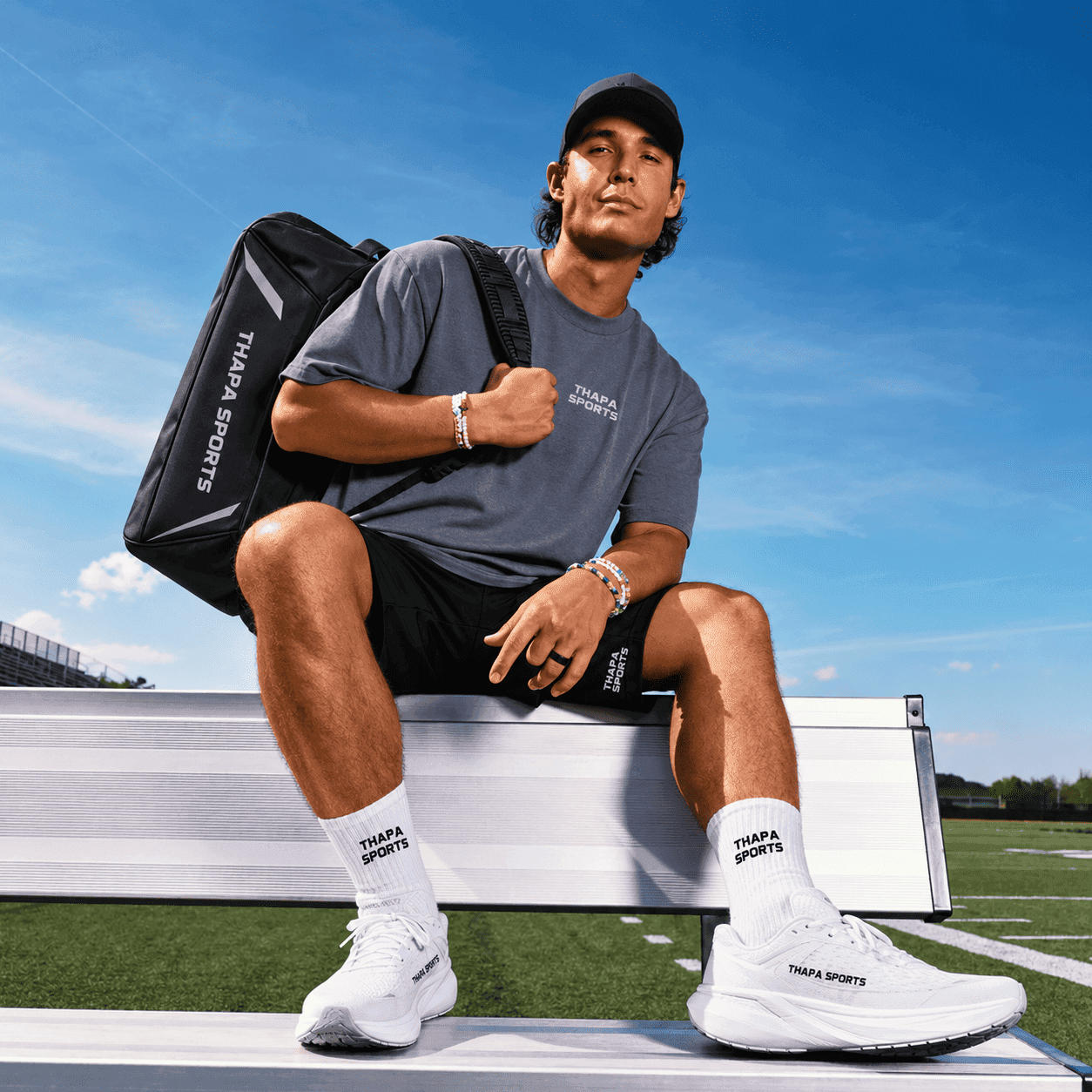 Thapa Sports athlete in studio kit, sitting on a sideline bench with the brand duffel.
